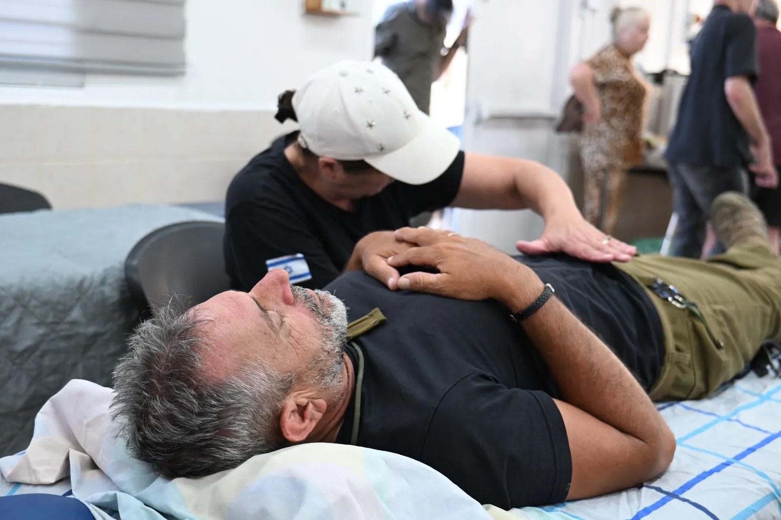 A volunteer offering gentle therapeutic touch to a soldier lying down