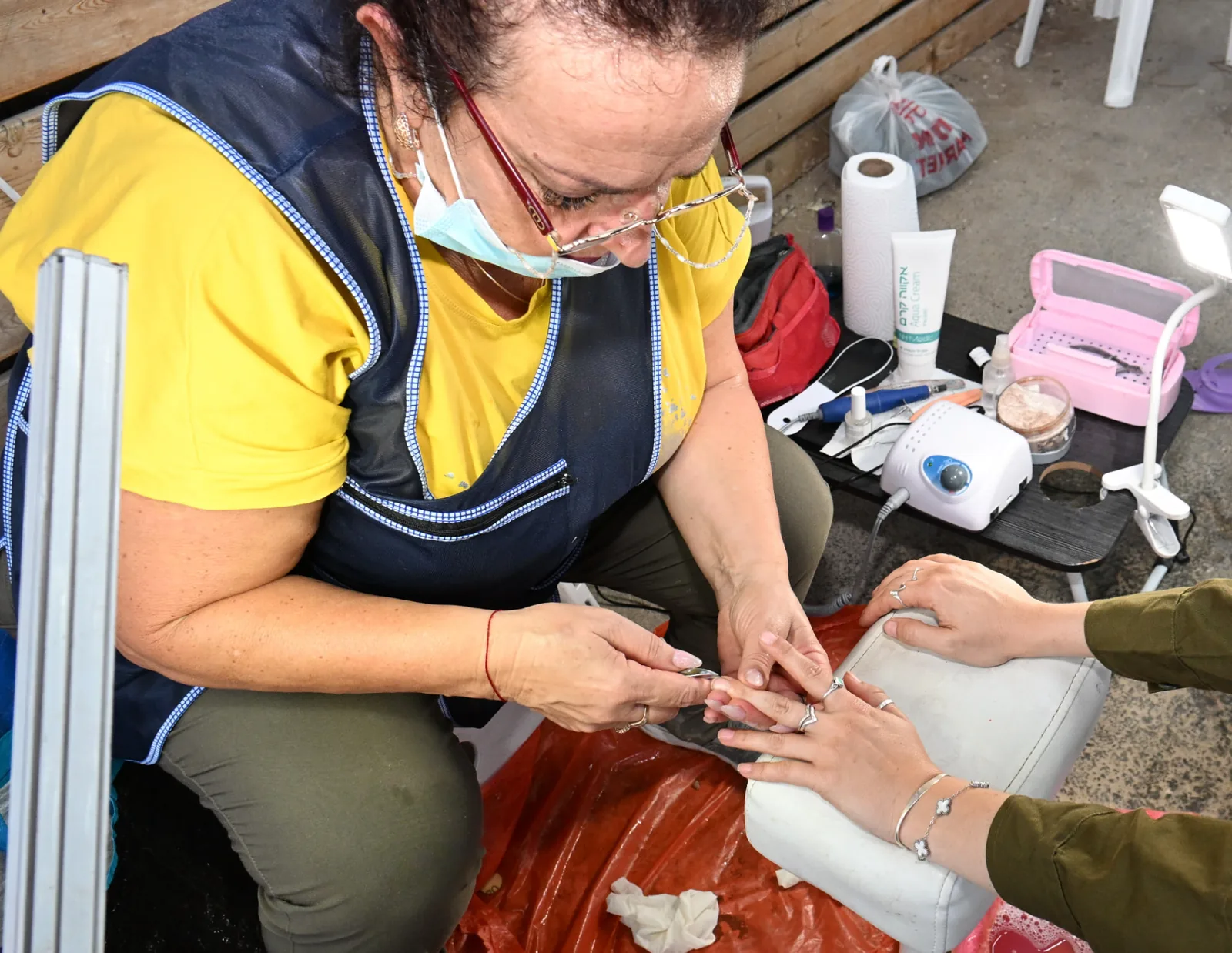 A volunteer manicurist caring for a female soldier's hands