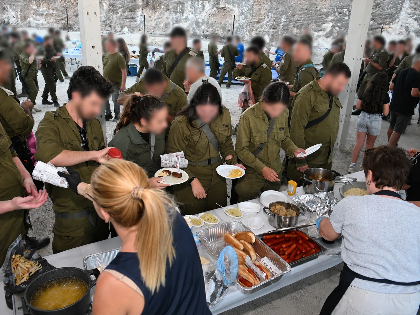 Soldiers receiving hot food from volunteers serving at a buffet line