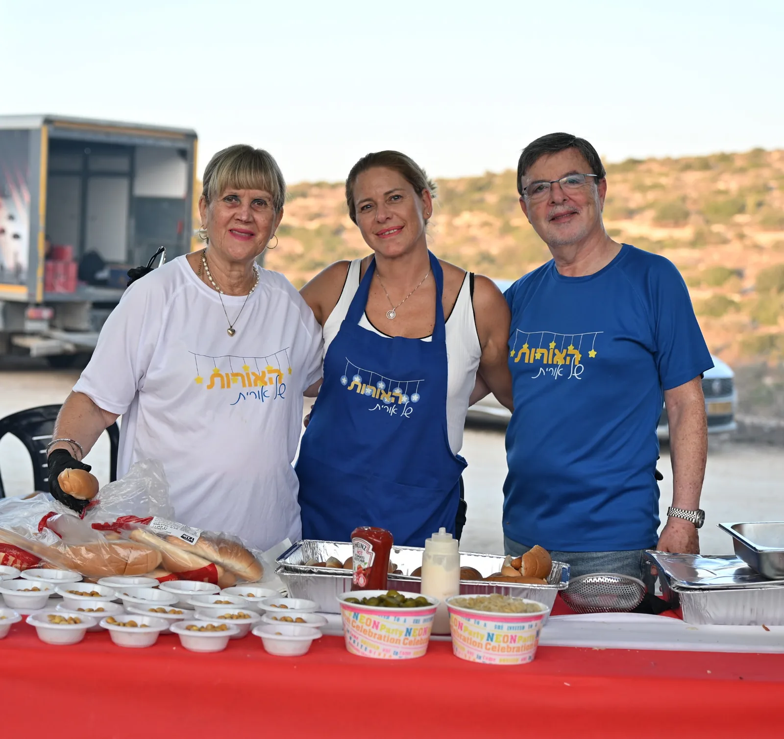 Three volunteers behind the serving table of rolls and salads