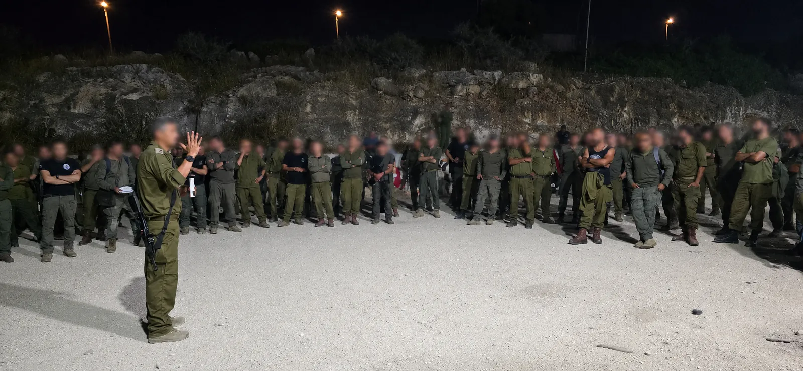 A commander addressing the assembled soldiers in the evening