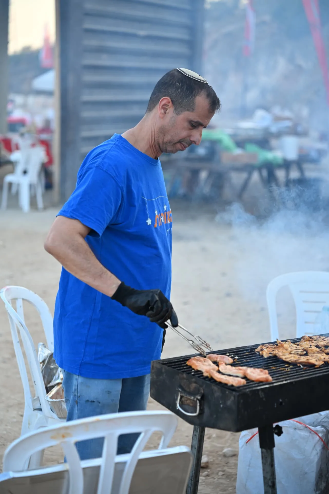A volunteer grilling meat over the coals