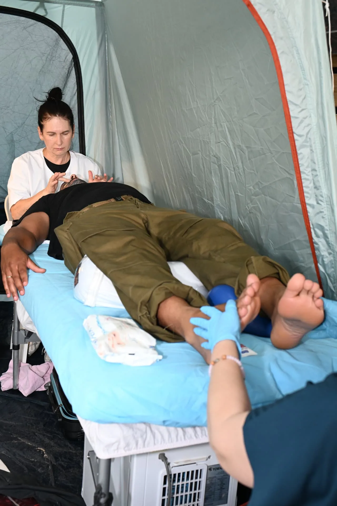 Two volunteers giving a soldier a treatment inside the quiet therapy tent