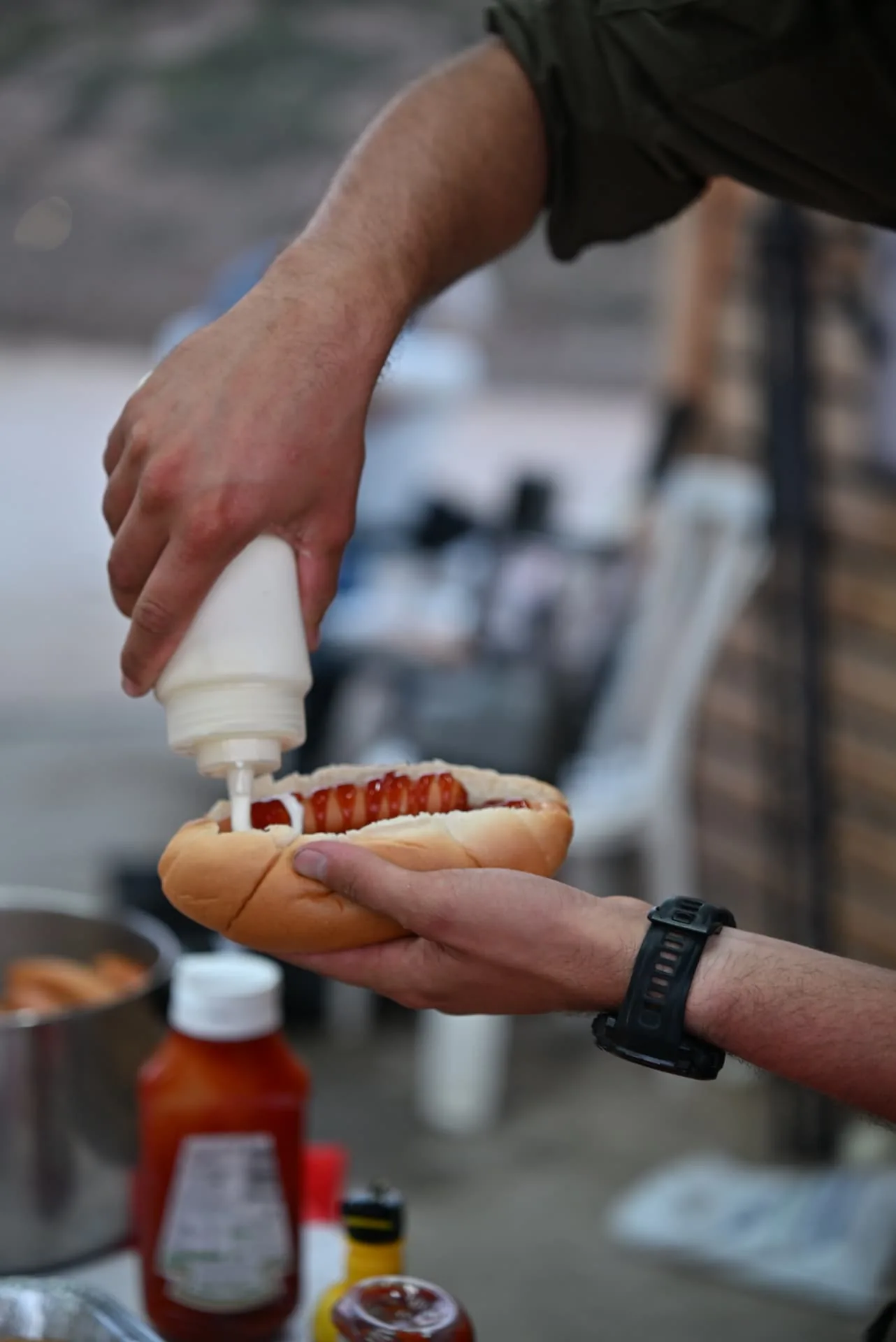 A soldier receiving a hot dog with sauce