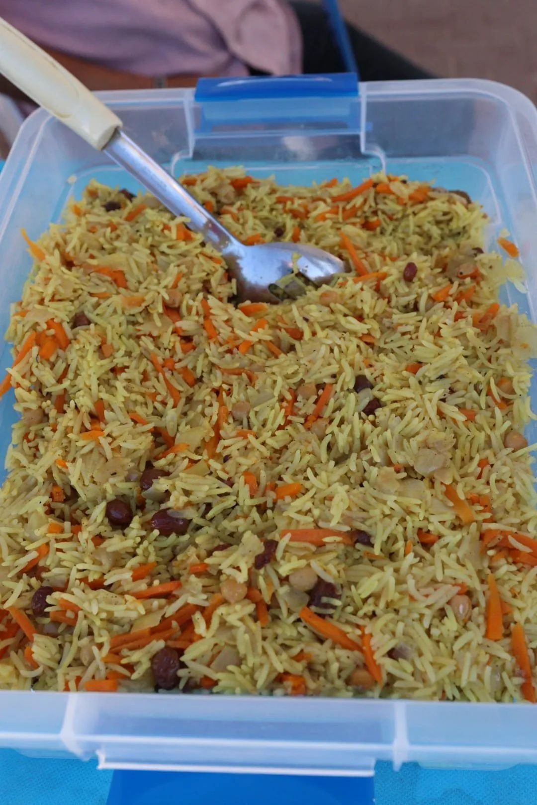 A large container of seasoned rice with carrots and chickpeas for the meal