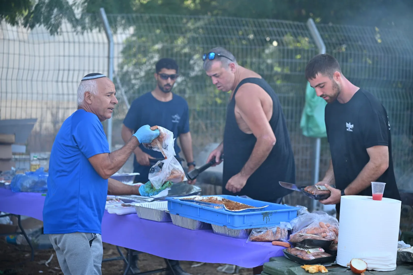 Volunteers loading the grill with meat and sausages
