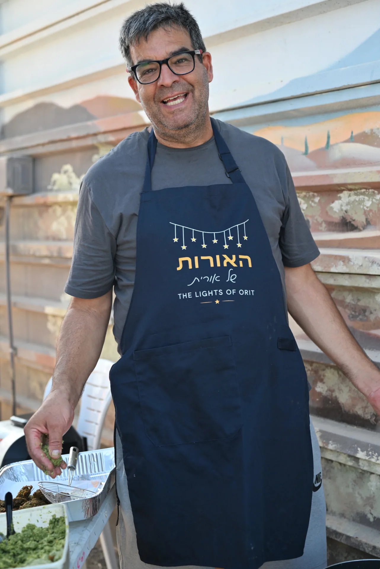 A volunteer in a Lights of Orit apron at the grill