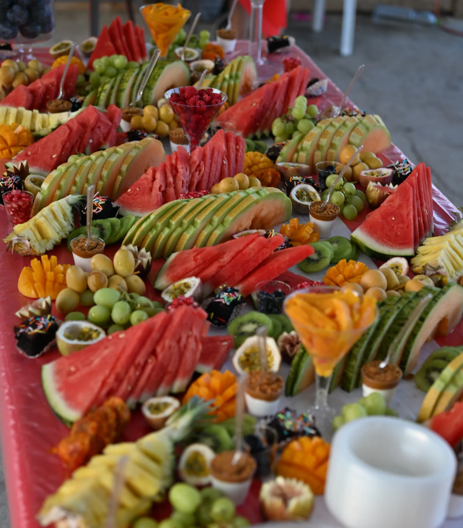 A long table of sliced fresh fruit and desserts