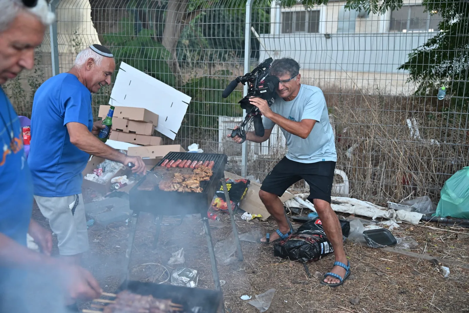 A camera operator filming a volunteer at the grill