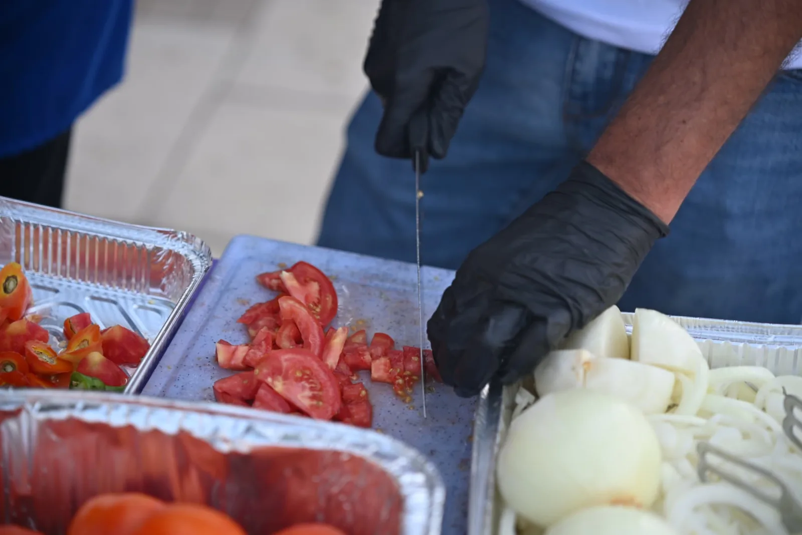 Hands slicing fresh tomatoes and onions