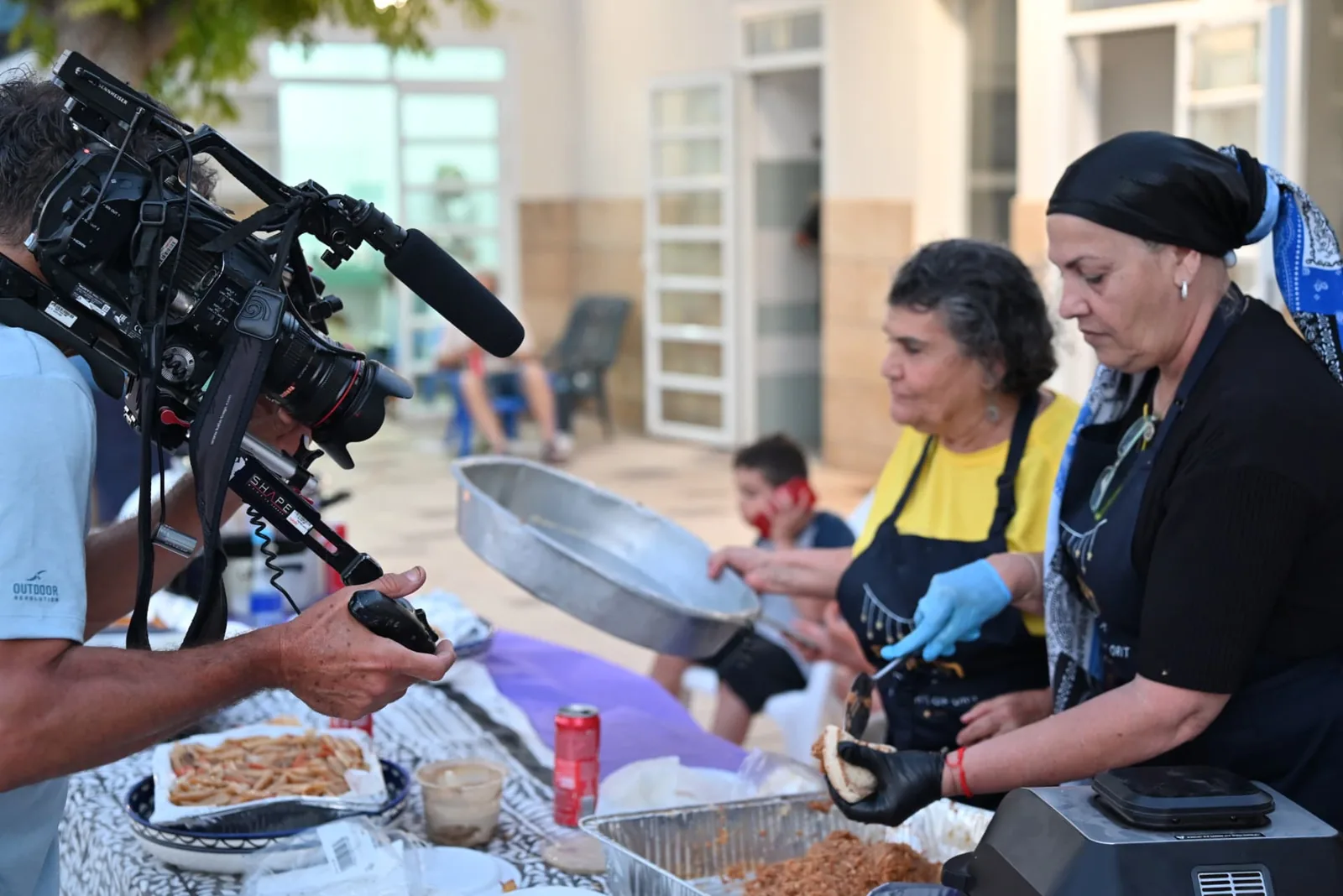 Television crew filming volunteers serving food