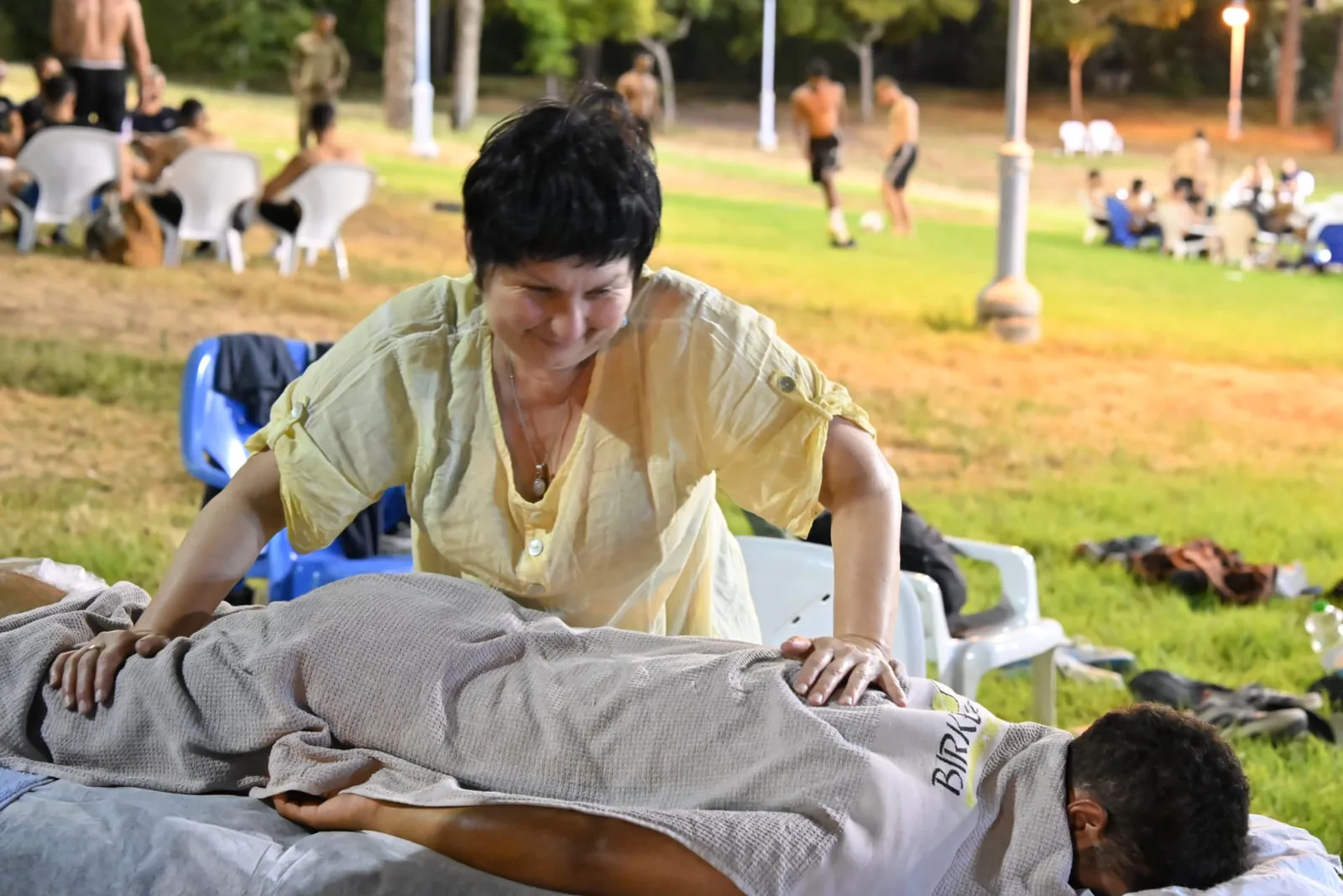 Volunteer therapist giving a massage on the lawn at dusk