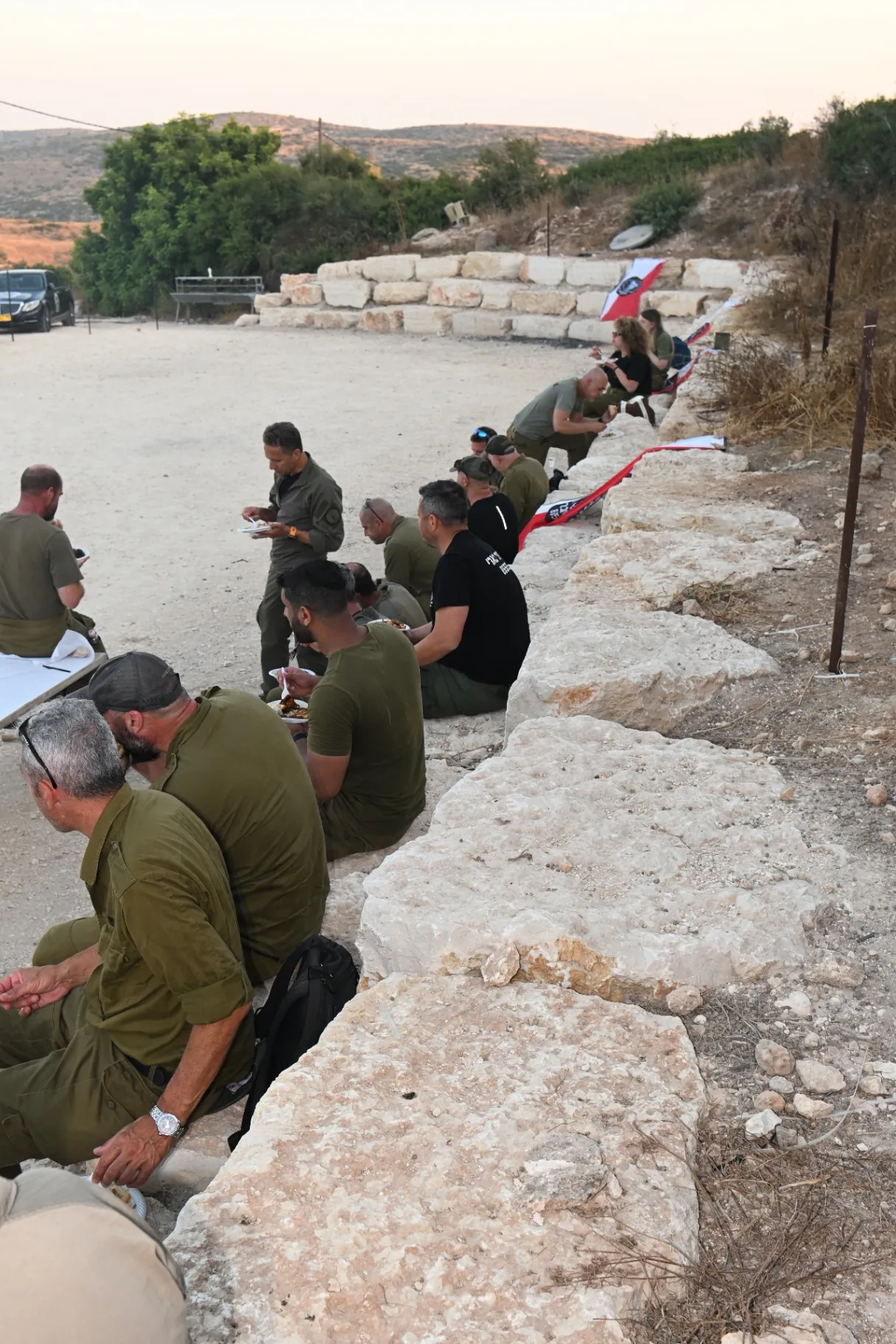 Soldiers seated together sharing a meal at sunset