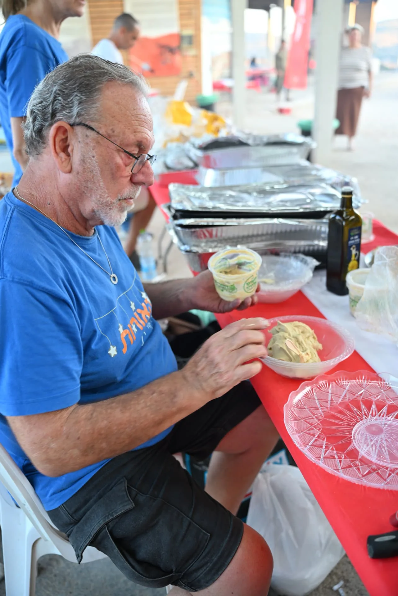 A volunteer preparing hummus bowls at the buffet