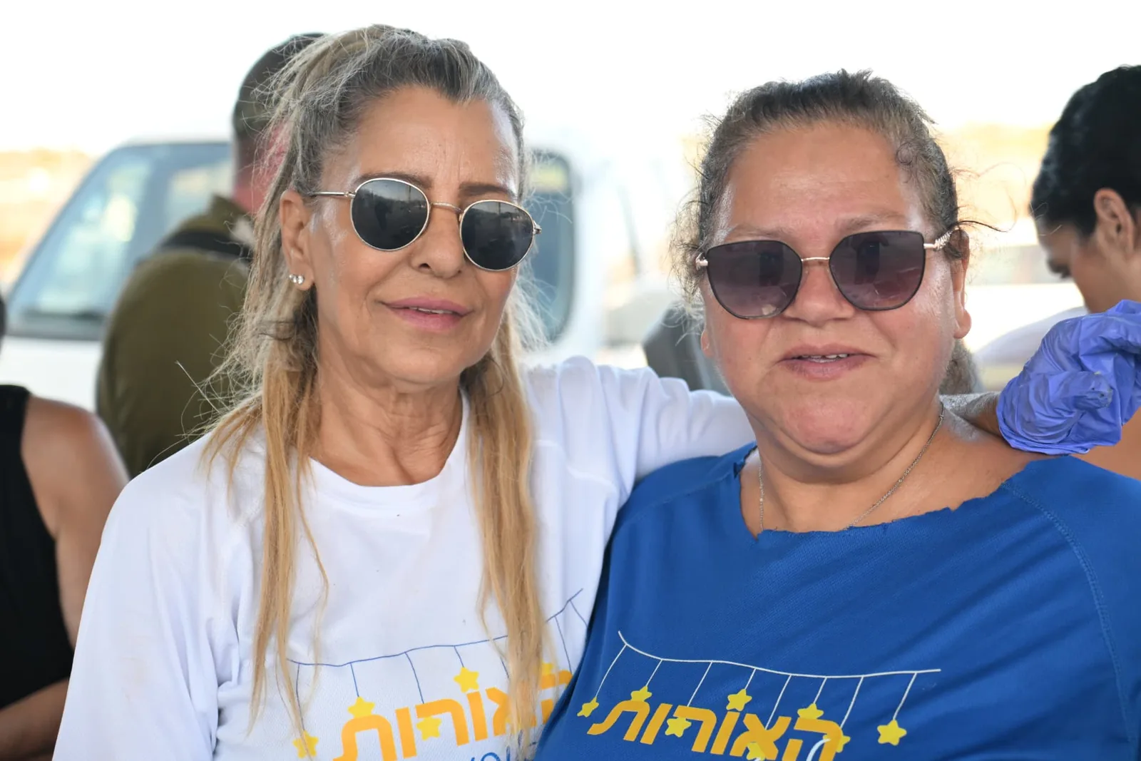 Two Lights of Orit volunteers in branded shirts pausing together during the event