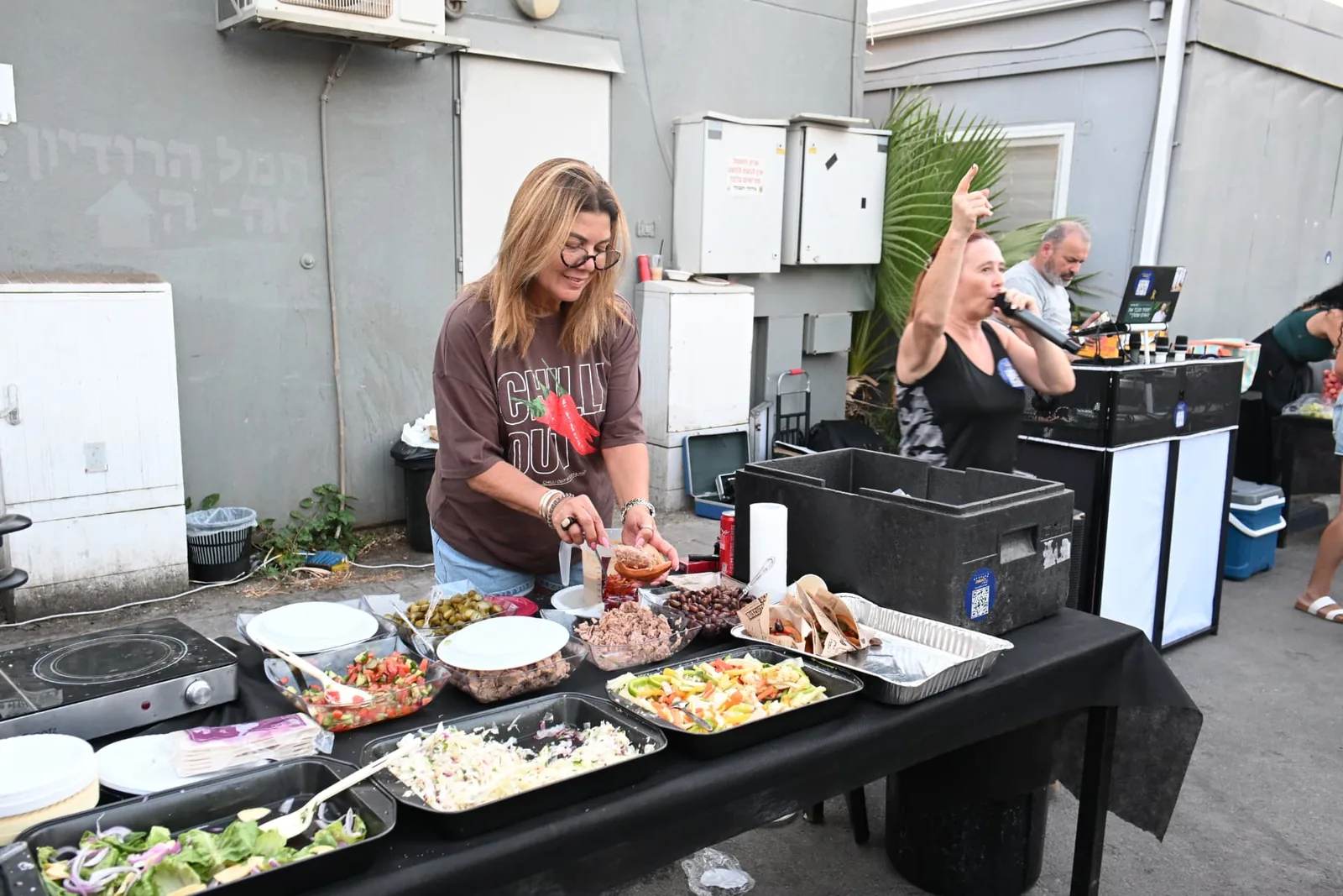 A volunteer preparing fresh salads and mezze at the serving table