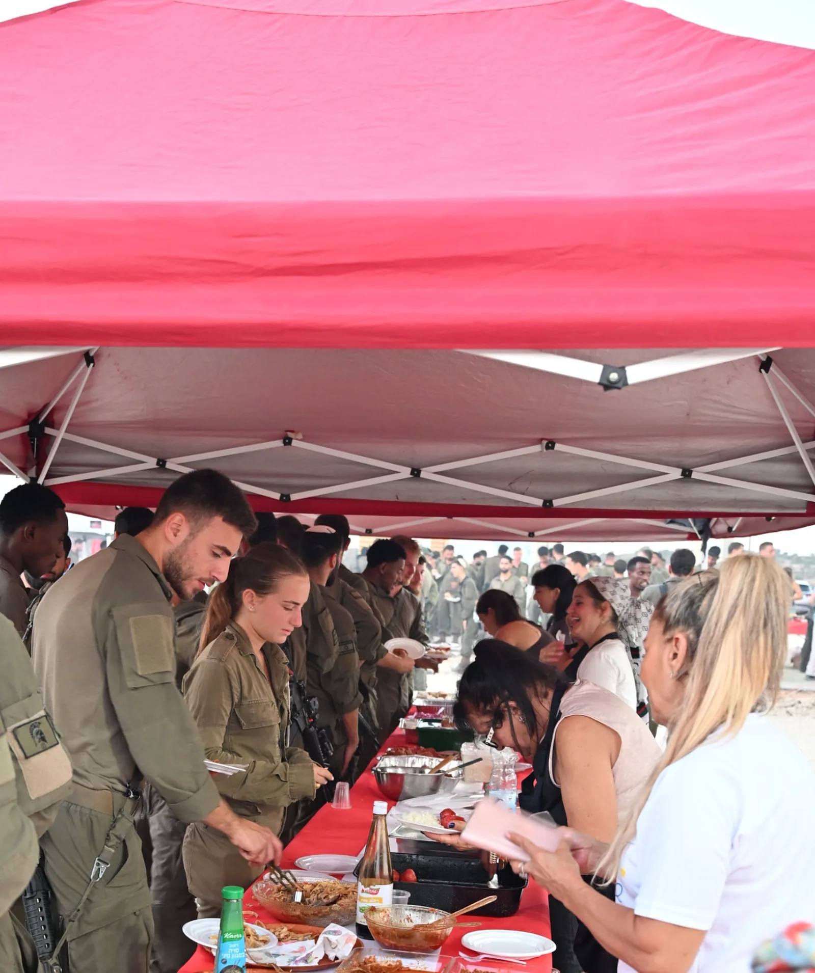 Soldiers and volunteers along the buffet line under the tent