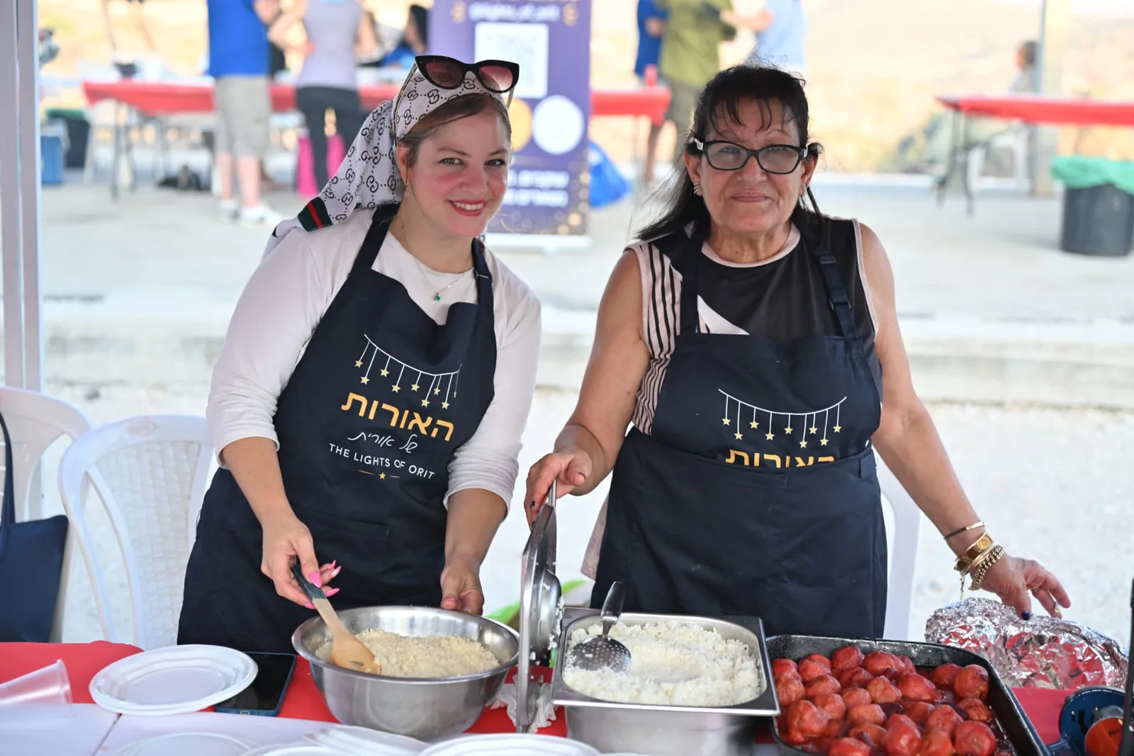 Volunteers in branded aprons serving couscous and meatballs