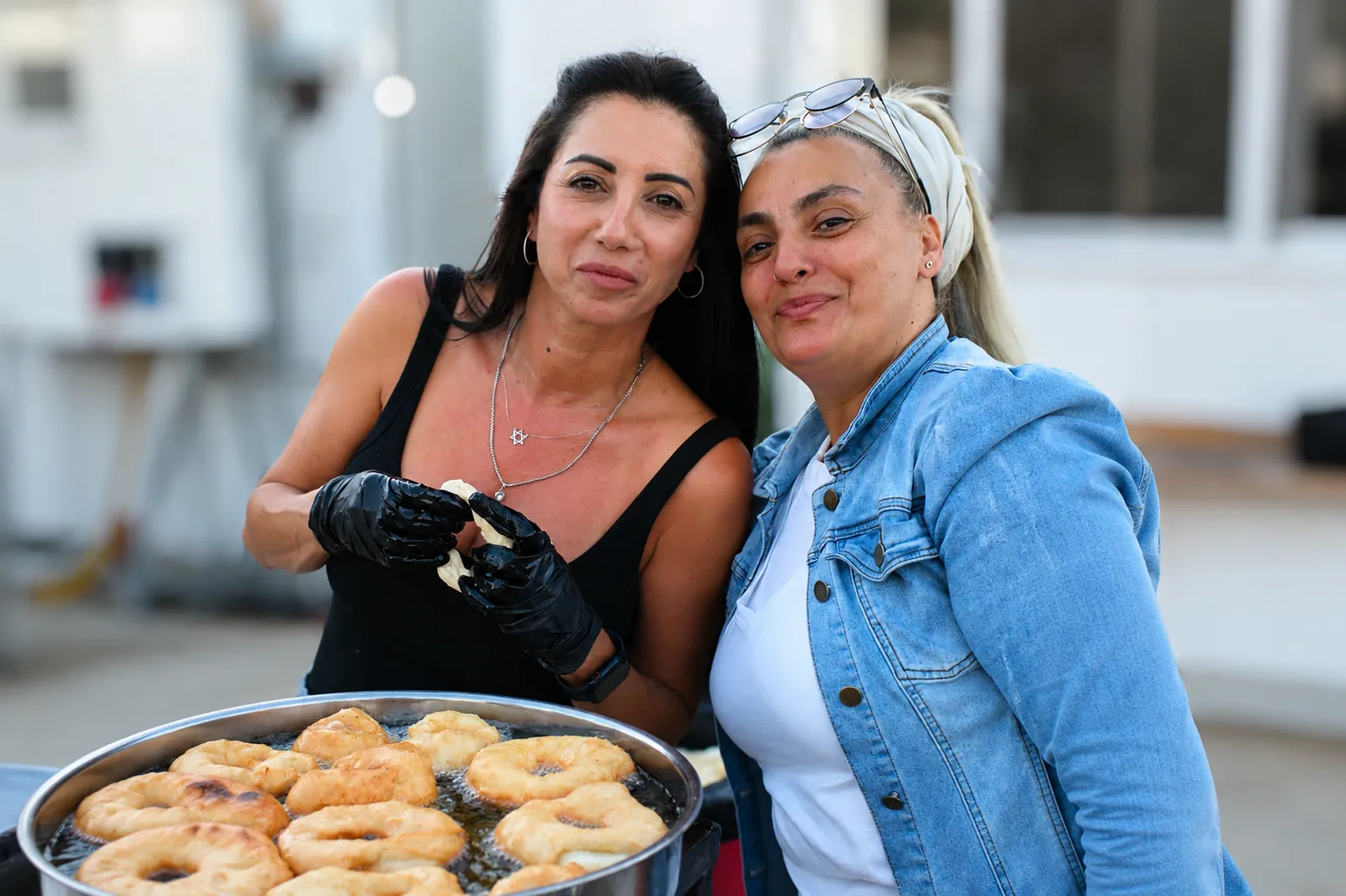 Two volunteers smiling beside a pan of fresh pastries at the Arbel event