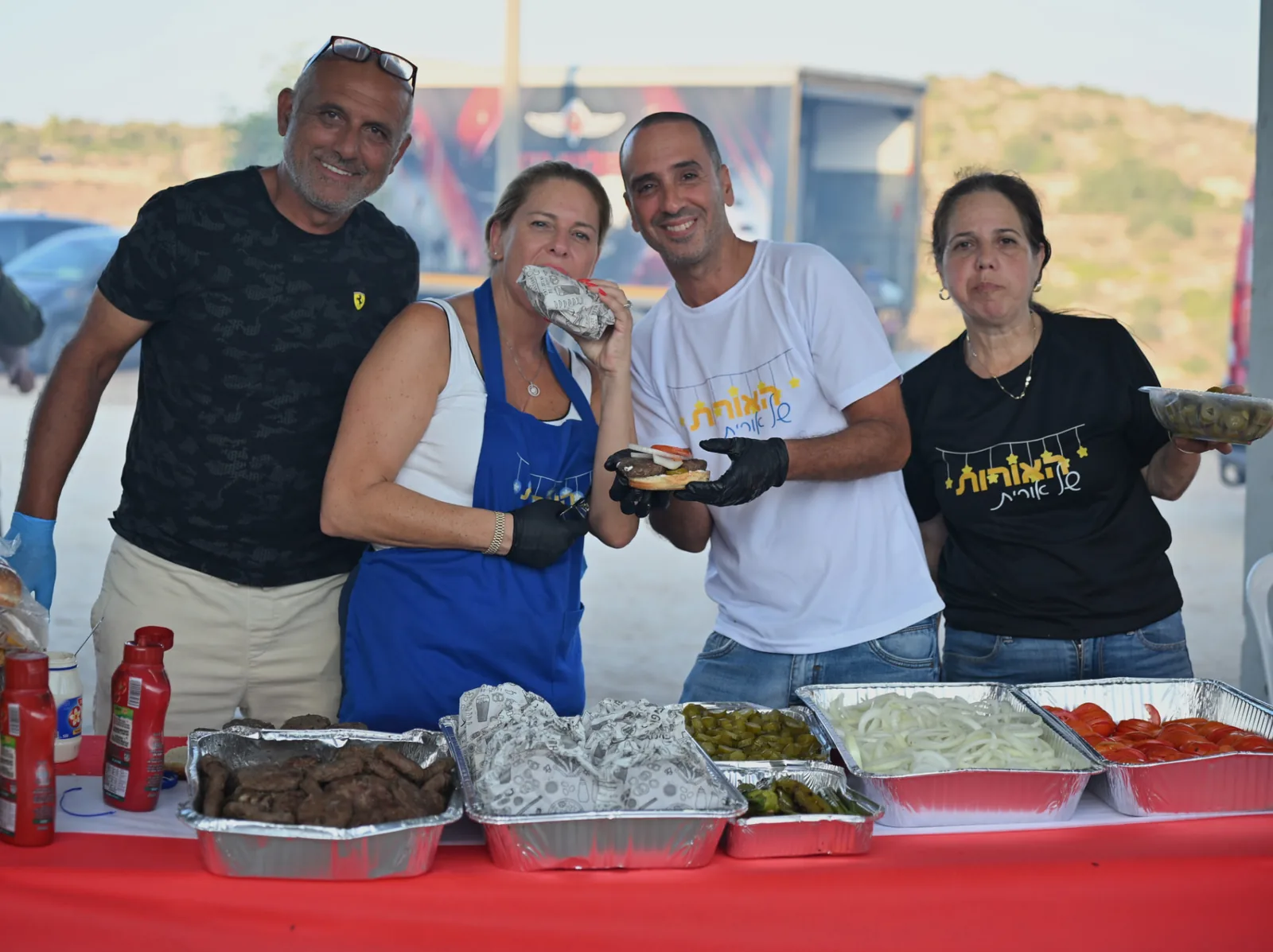 Volunteers smiling behind trays of grilled food