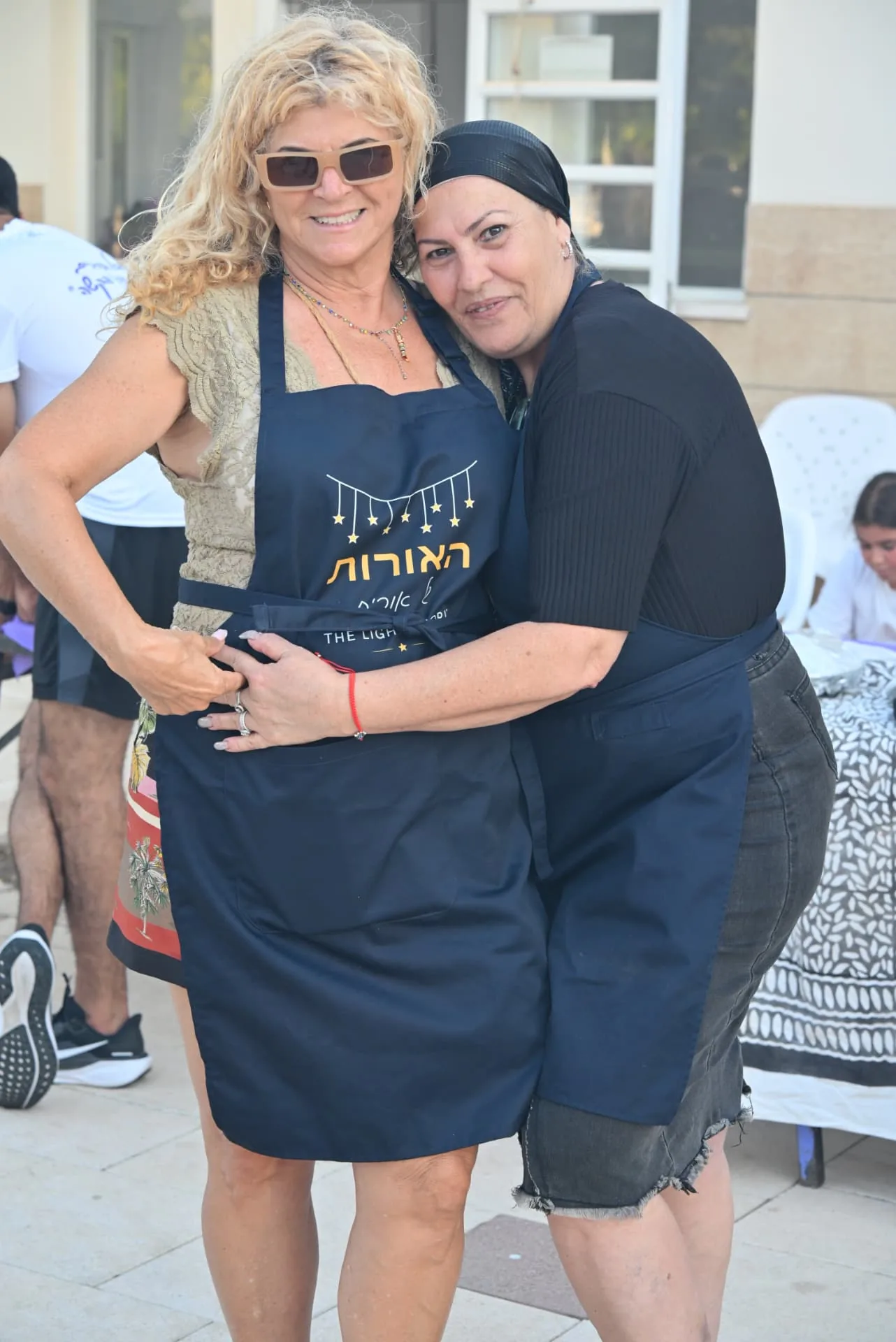 Two volunteers in Lights of Orit aprons embracing