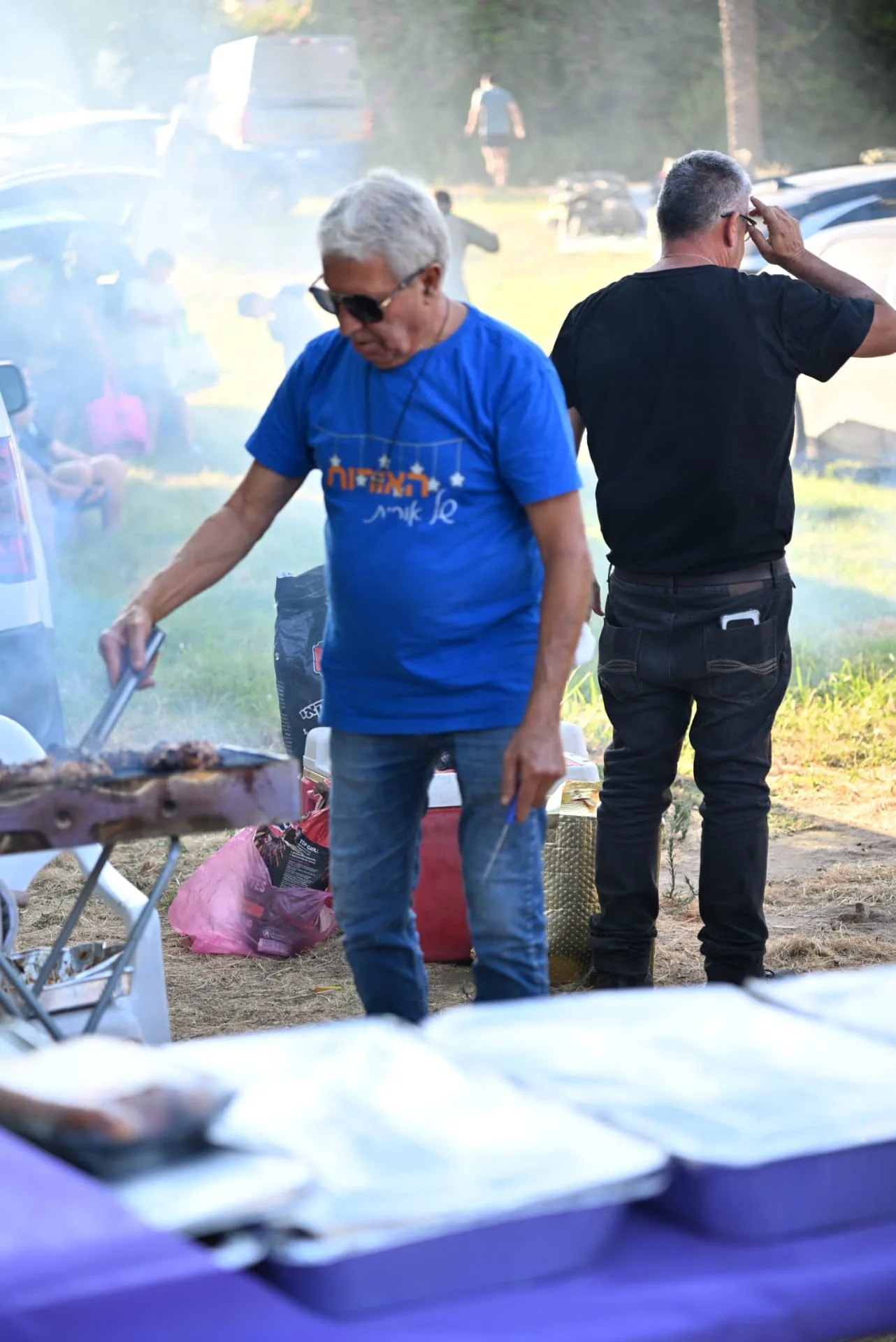 Volunteers tending the grill as smoke rises