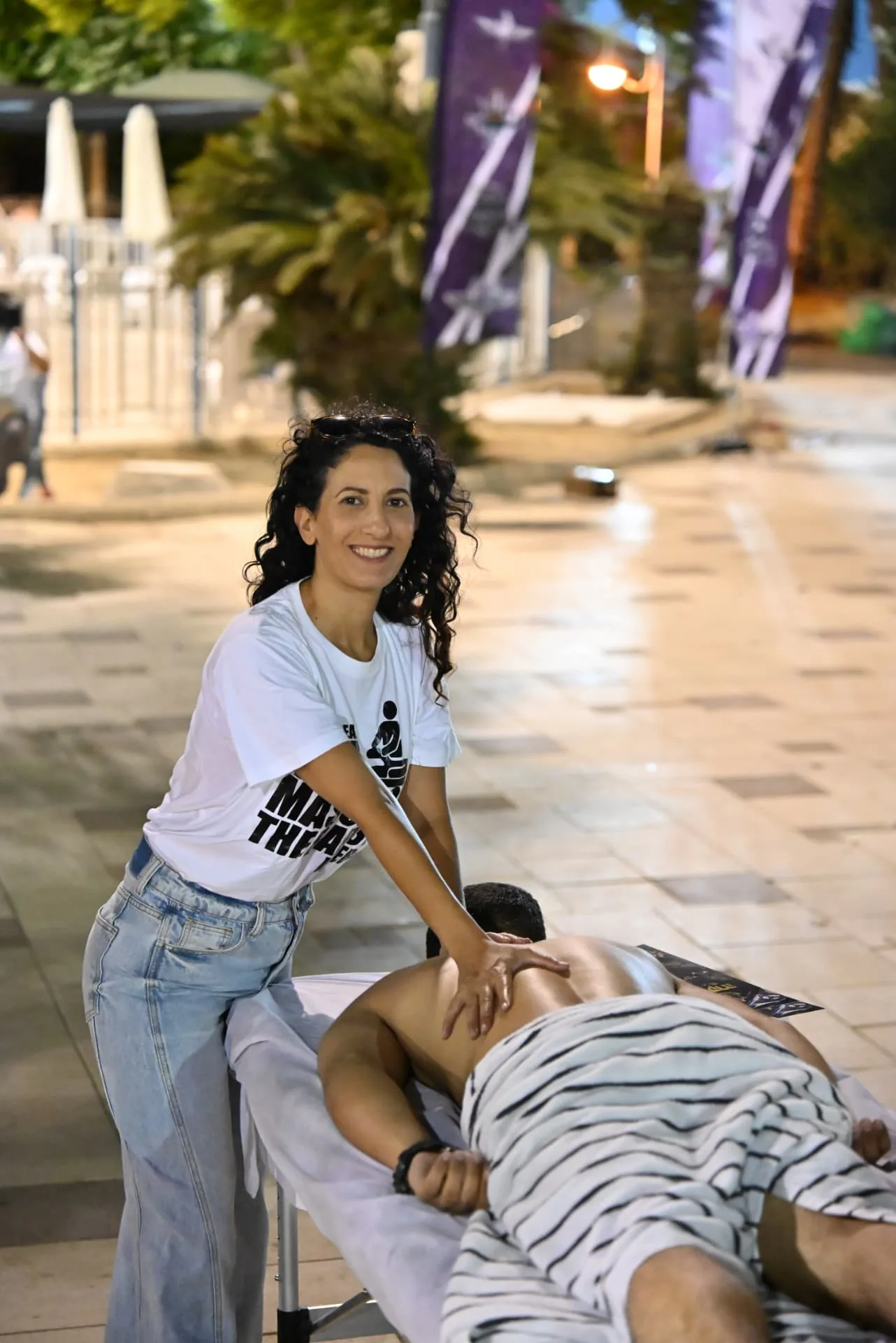 Smiling therapist at the night-time massage station