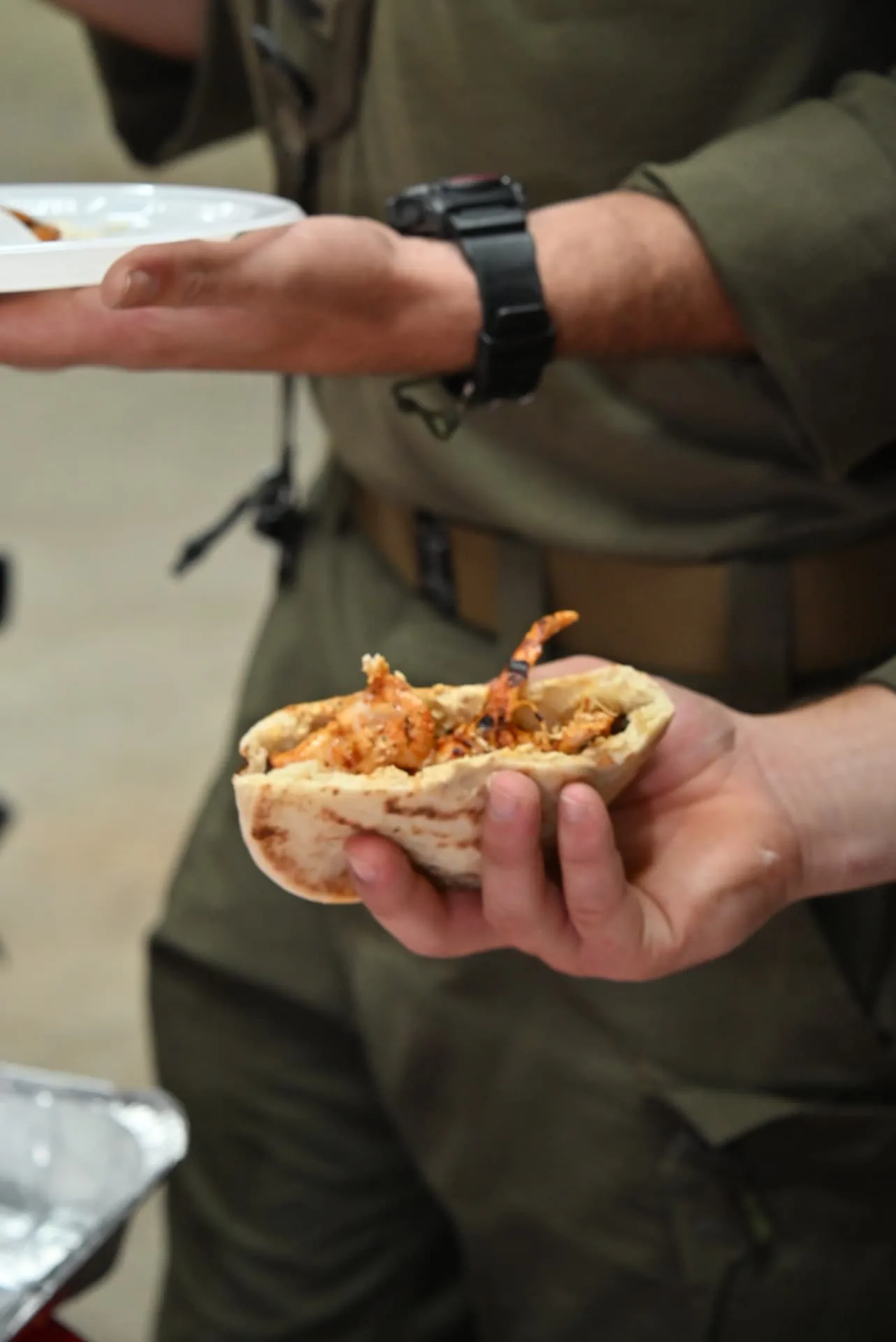 A soldier holding a pita filled with grilled chicken