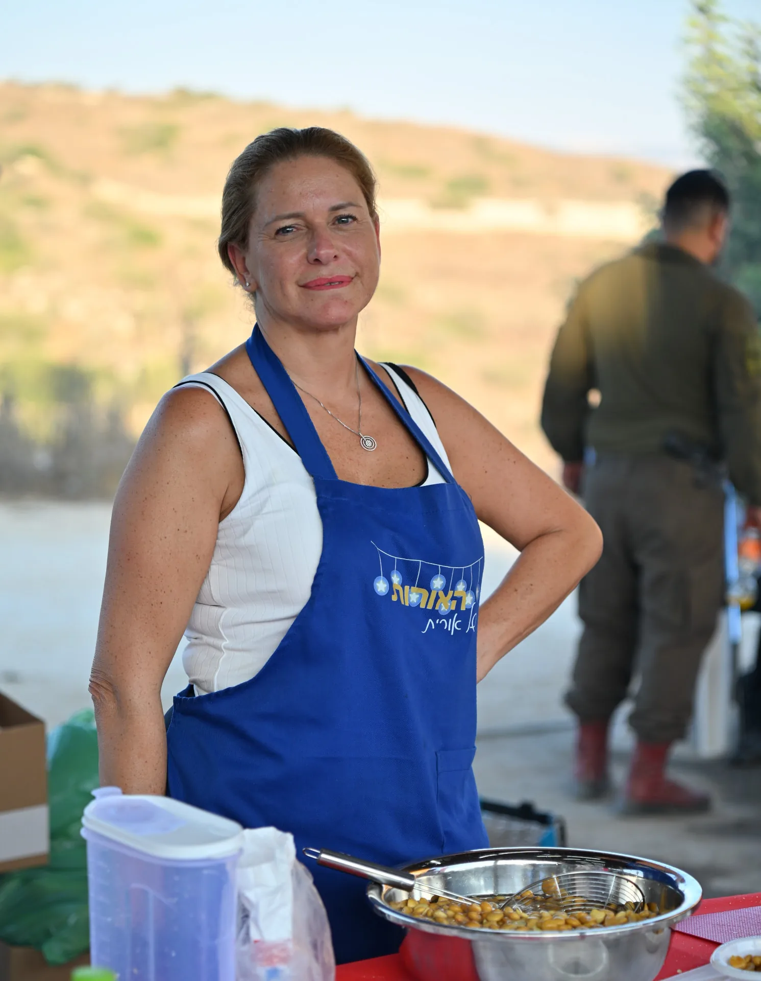 A volunteer in a branded apron beside the field kitchen