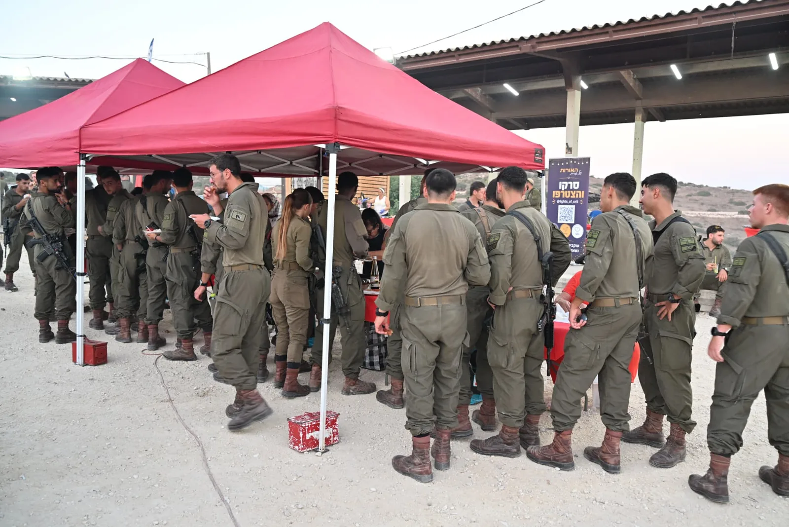 Soldiers gathered under the hospitality tents at dusk