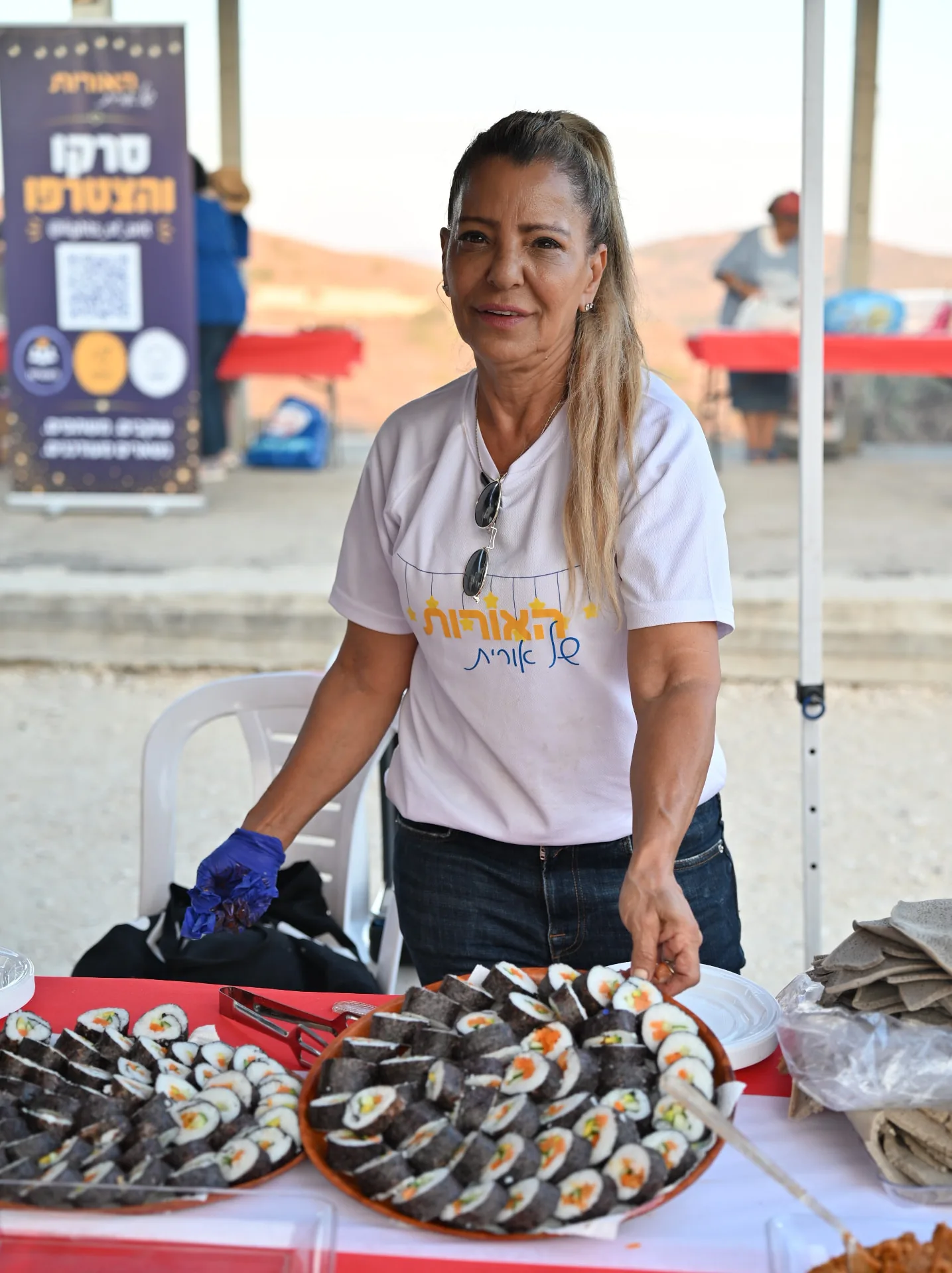 A volunteer arranging platters of sushi rolls