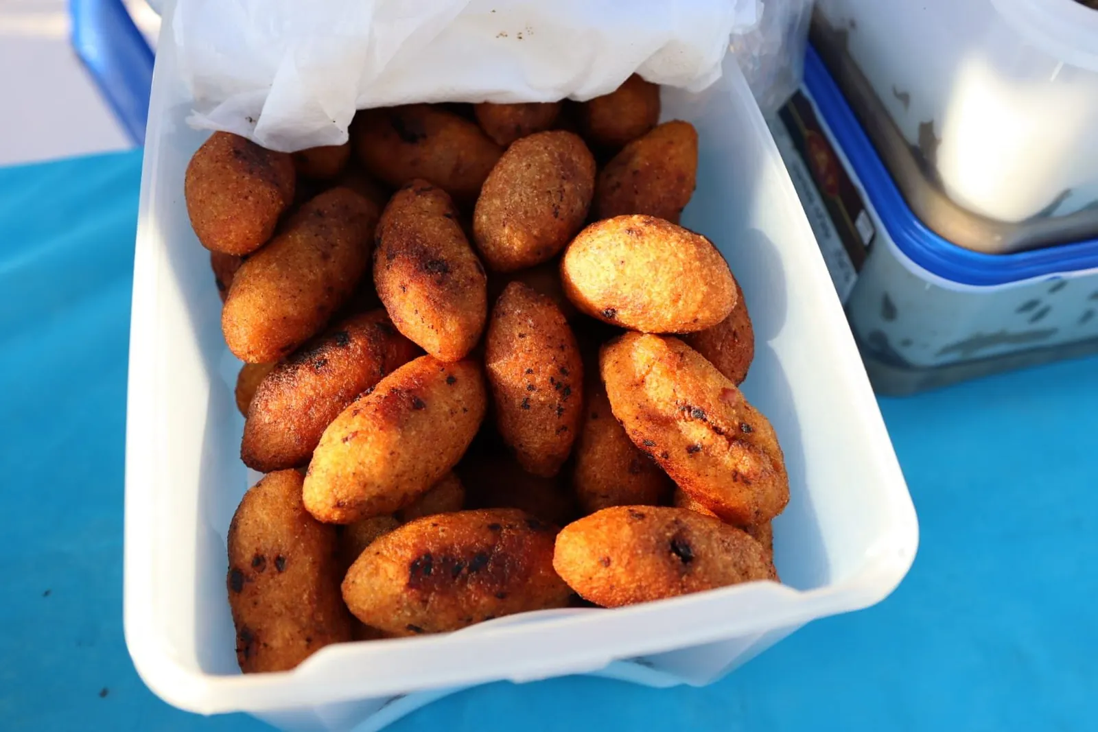 A container of golden fried savory fritters prepared for the soldiers