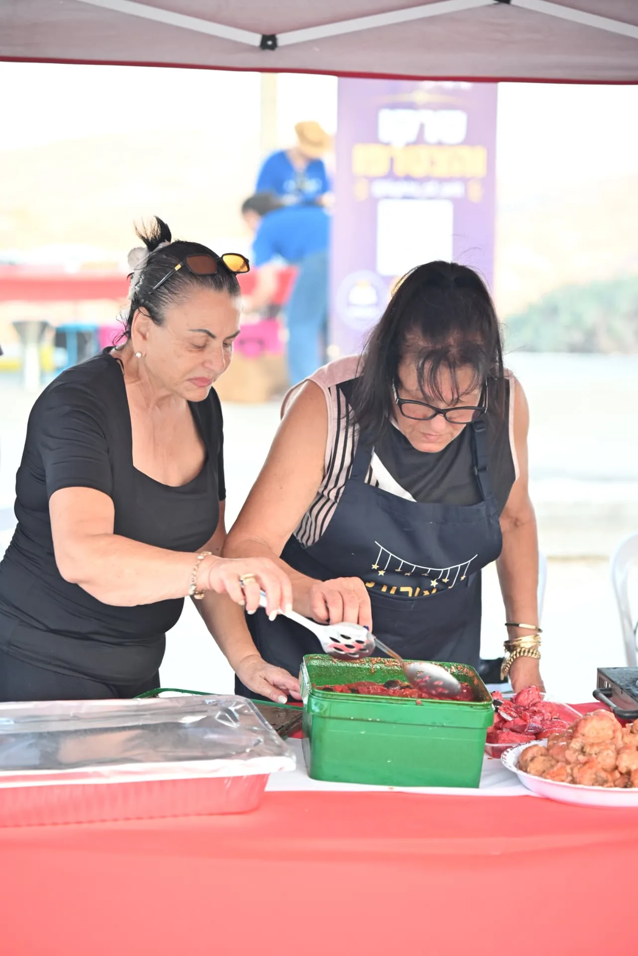 Two volunteers serving hot dishes together